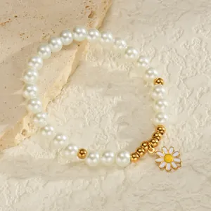 Gros plan d'un bracelet en perles avec billes dorées et pendentif marguerite blanche