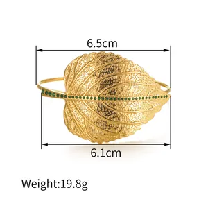 Goldenes Blatt-Armreif mit grünen Kristallen und hohlgeprägten Adern auf Weiß