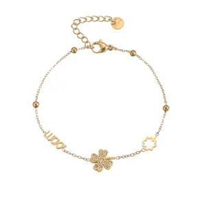 Detail of gold lucky clover bracelet with crystals and stainless steel charms on white background