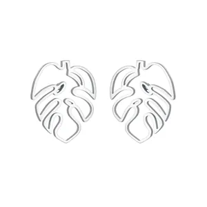 Détail macro de boucles d'oreilles feuille de monstera en acier argenté au design ajouré