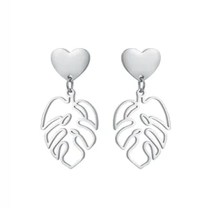 Détail de boucles d'oreilles cœur argenté avec pendentifs feuille de monstera évidée