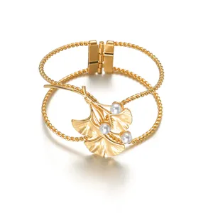 Detailaufnahme eines hohlen Federarmreifens mit goldenen Ginkgoblättern und weißen Perlen