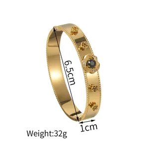Detail van 18K vergulde armband met roosmotieven, zwarte steen, 6,5 cm diameter en 1 cm breedte