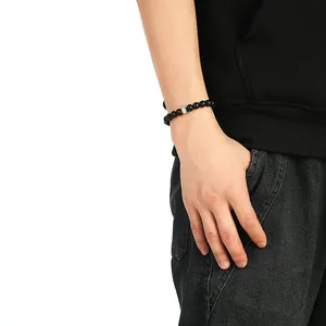 Nahaufnahme eines Herrenarmbands mit mattschwarzen Perlen und einer regenbogenfarbenen Perle
