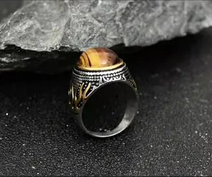 Macro detail of men's vintage ring featuring tiger eye stone and golden flame relief