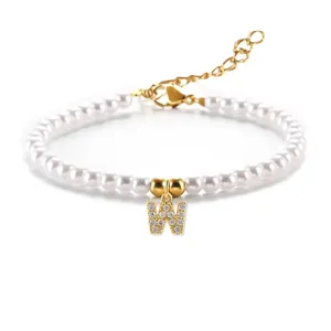 Detail van parelarmband met goudkleurige letter W hanger en glanzende kristallen