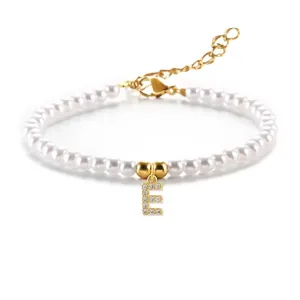 Macro-opname van parelarmband met sprankelende gouden letter E hanger en karabijnsluiting