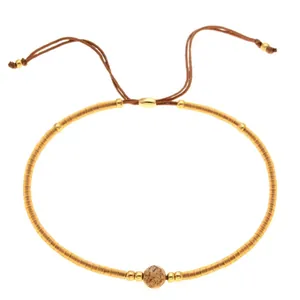 Bracciale bohémien con perline dorate e una pietra naturale marrone centrale lucida