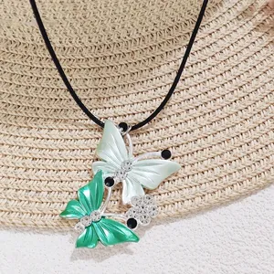 Detailed macro of green butterfly pendant with rhinestones on black woven choker cord