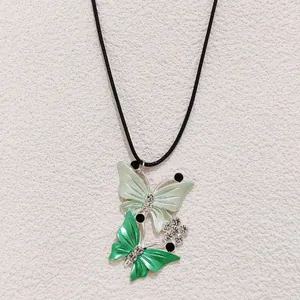 Detail of butterfly pendant with green enamel and rhinestones on black cord
