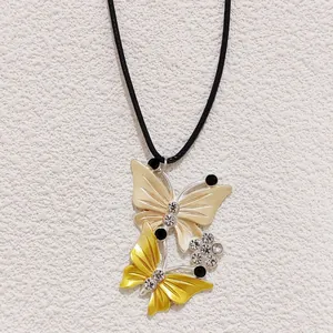 Close-up of yellow butterfly pendant with rhinestones and black beads on a black cord