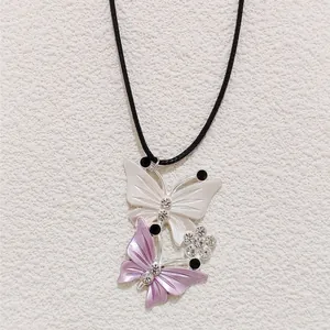 Detail of pearlescent butterfly pendants with crystal accents on a black cord necklace