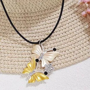 Necklace with gold and silver butterfly pendants on black leather cord, crystal details