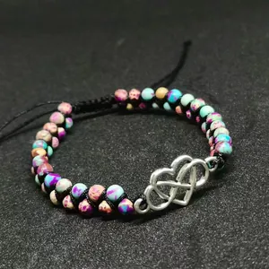 Bracelet tressé en pierre impériale avec breloque cœur infini argentée sur fond noir mat