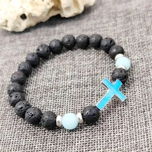 Luminous lava stone bead bracelet with a blue cross pendant on a grey textured background