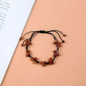 Détail du bracelet tissé à la main avec pierres d'agate rouge et cordon noir réglable