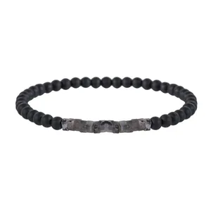 Macro detail of matte black beads and rectangular textured tiger eye stones on the bracelet