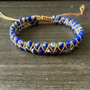 Detalle de la pulsera tejida a mano con cuentas azules y cordón marrón ajustable