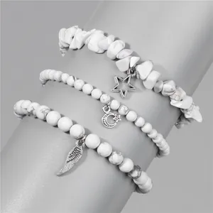 Detail view of white natural stone bead bracelets with star, moon and wing pendants