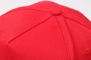 Macro detail of the top button and stitching on a premium red cotton baseball cap