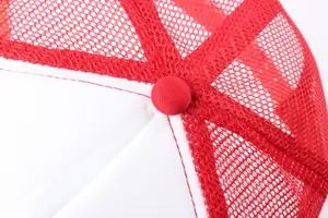 Macro view of a red and white trucker hat showing mesh texture and top fabric button