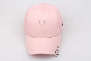 Detail einer rosa Baumwoll-Basecap mit Metallringen am Schirm und seitlicher Stickerei