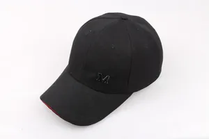 Dettaglio cappello baseball nero con logo M metallico e bordo rosso a contrasto