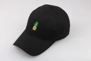 Détail d'une casquette de baseball noire en coton avec broderie de l'ananas jaune vif