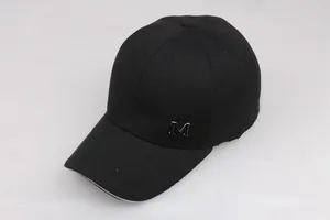 Dettaglio del cappellino nero in cotone con logo M in metallo e trama in twill