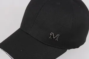 Dettaglio cappello baseball in twill nero con logo M in metallo e bordo della visiera