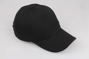 Dettaglio cappello nero da baseball con fibbia in metallo e bordo visiera a contrasto bianco
