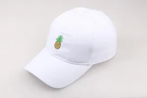Détail d'une casquette blanche avec une petite broderie d'ananas jaune et verte