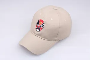 Detail showing the colorful Chinese Peking Opera mask embroidery on a beige cotton cap
