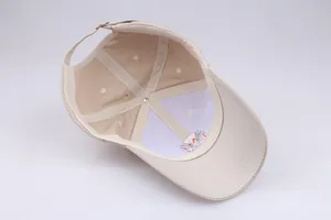 Detailed interior of beige cotton baseball cap showing embroidery back and metal buckle