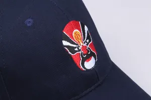 Macro shot of detailed Chinese Opera mask embroidery on navy cotton baseball cap