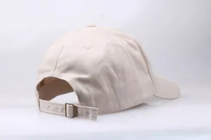 Detail of adjustable metal buckle and six-panel structure on cream cotton baseball cap