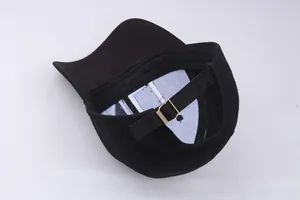 Detail showing the adjustable gold metal buckle and strap on back of black cotton baseball cap