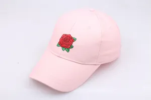 Close-up of red rose embroidery on a light pink cotton baseball cap with curved brim