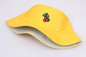 Close-up of red cherry embroidery on a yellow cotton canvas bucket hat detail