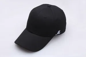 Détail d'une casquette de baseball noire avec broderie blanche de la lettre M latérale