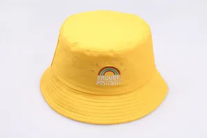 Detail of yellow canvas bucket hat featuring rainbow and Radiate Positivity embroidery