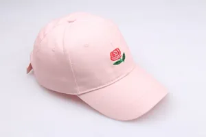 Close-up of pink cotton baseball cap featuring detailed red rose floral embroidery