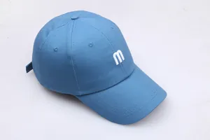 Detailweergave van wit M-letterborduurwerk op blauwe katoenen baseballpet met gebogen klep
