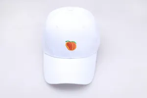 Gros plan sur la broderie de pêche détaillée sur le devant de la casquette blanche en coton