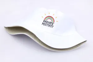 Close-up of rainbow embroidery and RADIATE POSITIVITY text on white cotton bucket hat