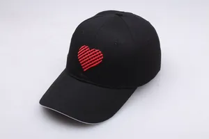 Schwarze Baseballkappe mit roter Herz-Stickerei, lässiger Baumwollstil auf grauem Boden
