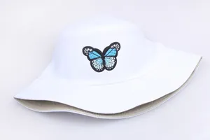 Detailaufnahme blauer Schmetterlingsstickerei auf weißem Fischerhut aus Baumwolle