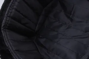 Detailed macro view of black quilted lining and soft faux fur trim on a winter trapper hat