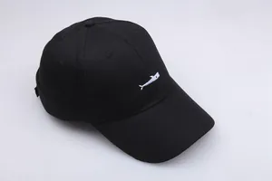 Close-up of a black cotton baseball cap featuring minimalist white fish embroidery detail