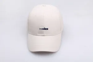 Detailed close-up of navy blue whale embroidery on a cream cotton baseball cap